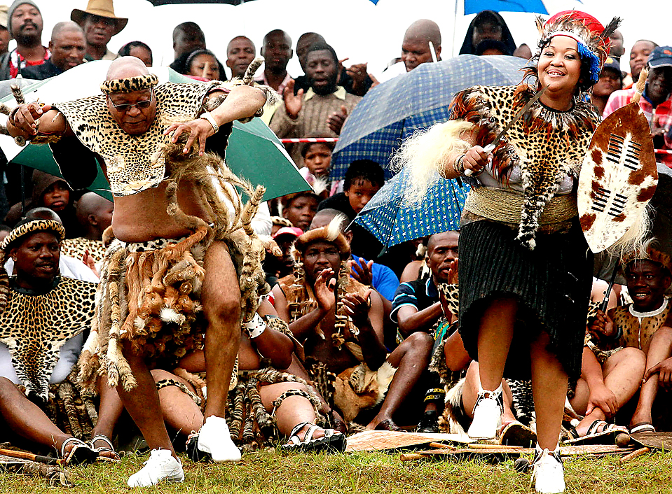 TOPSHOTS South African President Jacob Zuma (L), wearing leopard skins, sings and dances with his newlywed Thobeka Madiba (R) at their wedding ceremony on January 4, 2010 in a colourful Zulu traditional wedding outfit at Zuma's rural homestead of Nkandla, some 400 kilometres north of Durban. Wearing leopard skins and carrying a Zulu shield, South Africa's polygamous President Jacob Zuma on married today for fifth time, in a traditional ceremony in his remote hometown. The 67-year-old and his new bride Thobeka Madiba, 30 years his junior, danced in an open field at his homestead in Nkandla, a village deep in the countryside of KwaZulu-Natal province. AFP PHOTO / RAJESH JANTILAL (Photo credit should read RAJESH JANTILAL/AFP/Getty Images)