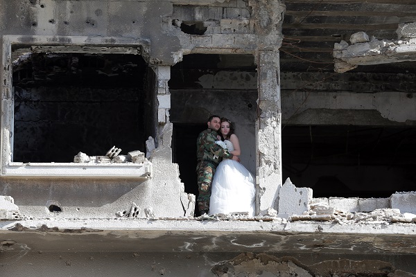 Newly-wed Syrian couple Nada Merhi,18, and Syrian army soldier Hassan Youssef,27, pose for a wedding picture amid heavily damaged buildings in the war ravaged city of Homs on February 5, 2016. A Syrian photographer thought of using the destruction of Homs to take pictures of newly wed couples to show that life is stronger than death.   / AFP / JOSEPH EID